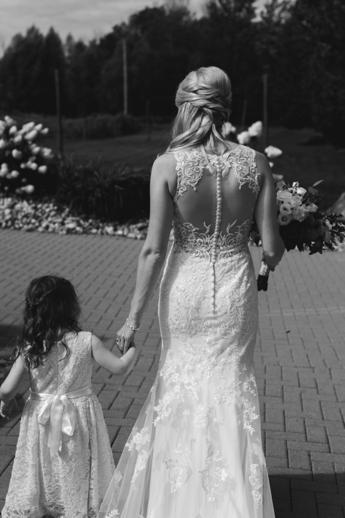 bride holding the flower girl's hand walking