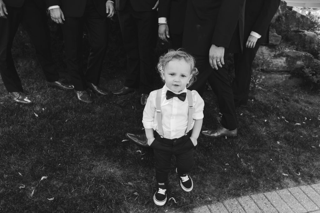ring bearer with his hands in pockets smiling at the camera