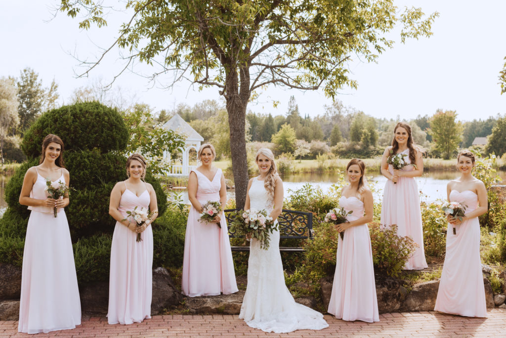 bridesmaids standing underneath tree smiling at the camera
