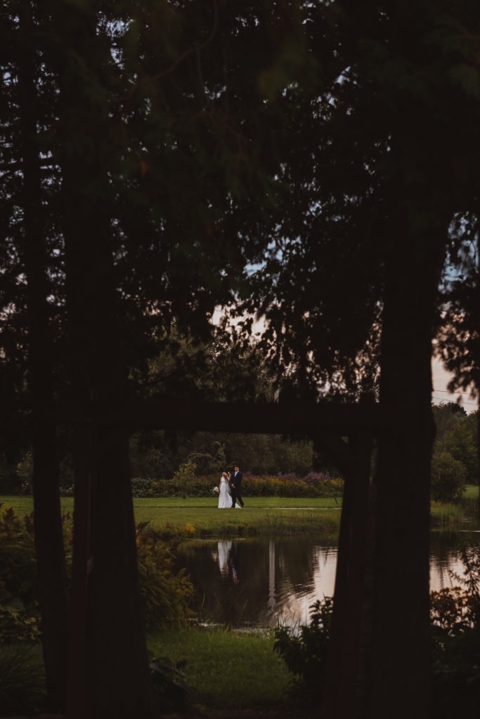 bride and groom walking by the water at sunset