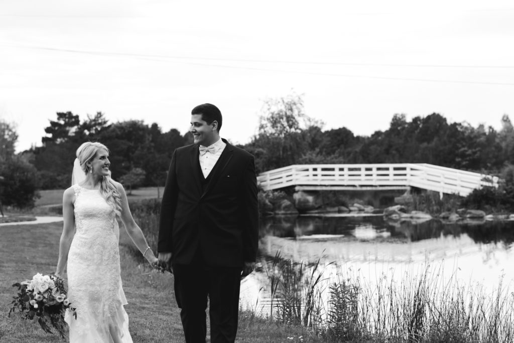 bride and groom walking by the water holding hands