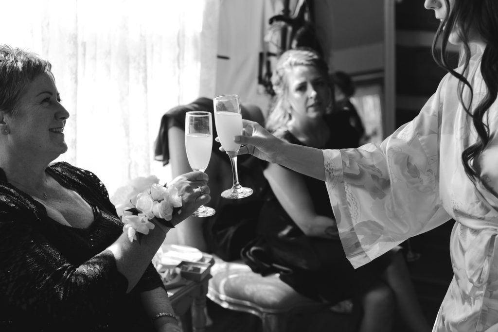 bride cheersing her mom with mimosa