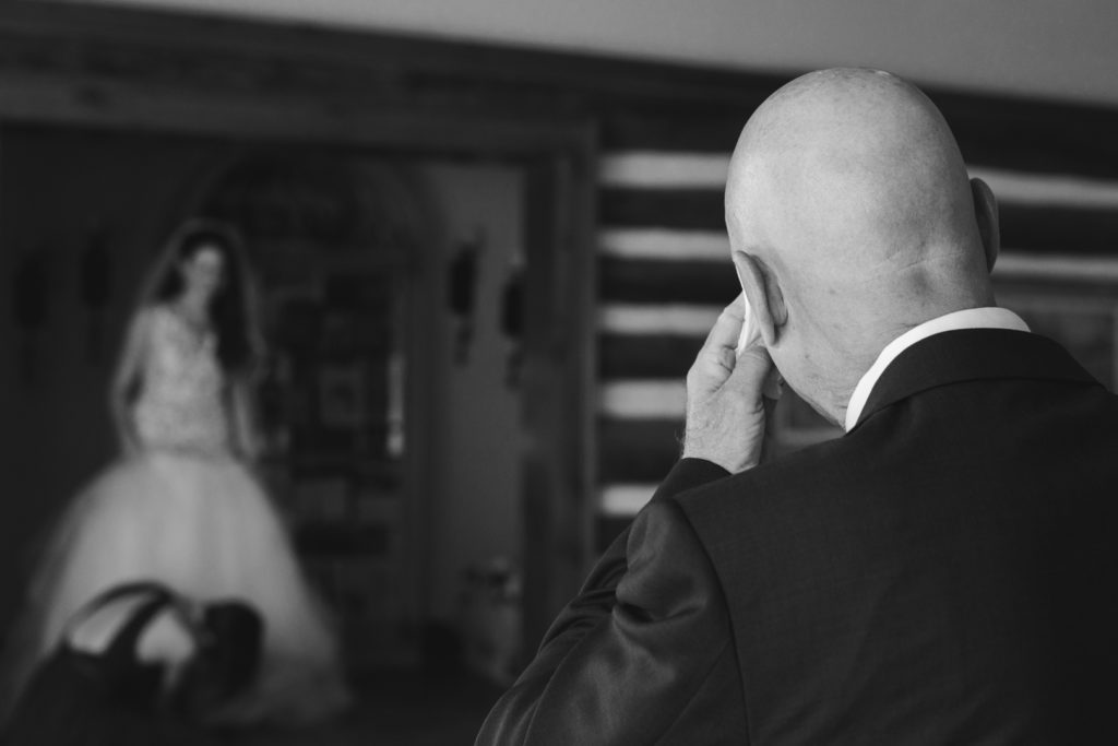 father of the bride wiping away a tear after seeing his bride in her wedding dress for the first time