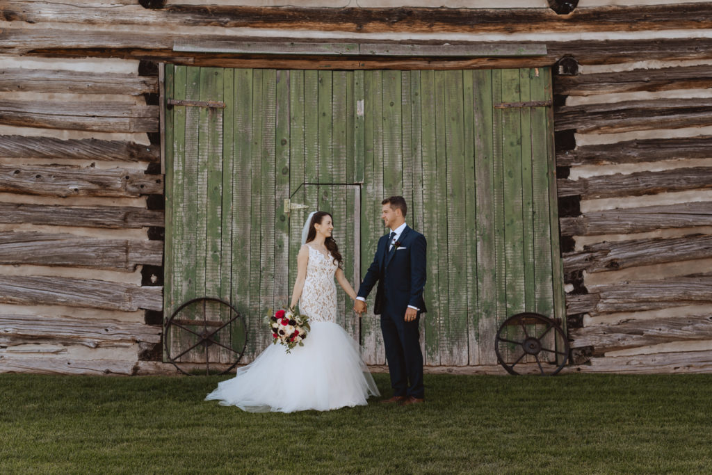 bride and groom holding hands in front of green barn door