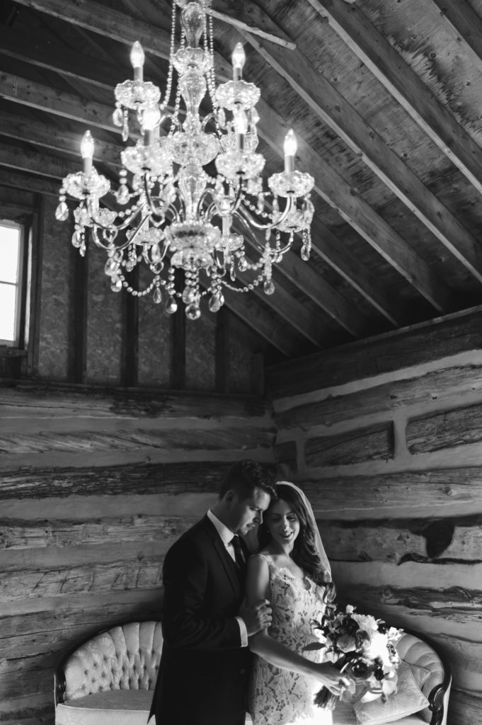 bride and groom standing in farm house with beautiful chandelier