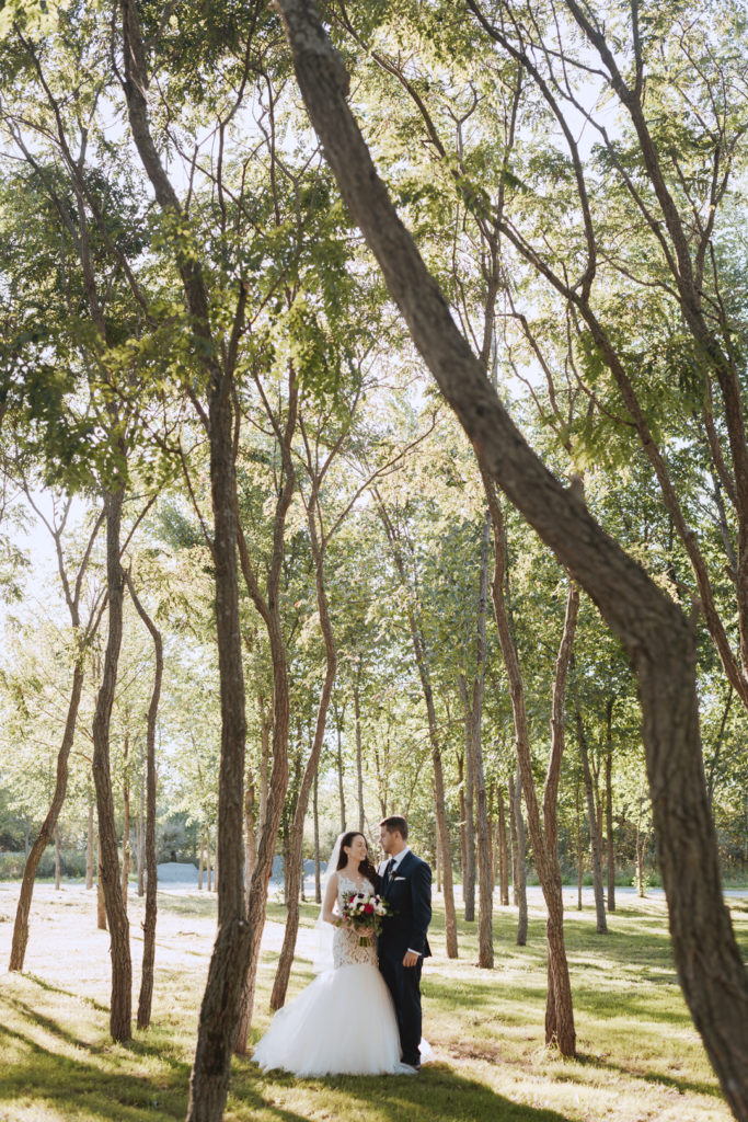 bride and groom standing among tall trees
