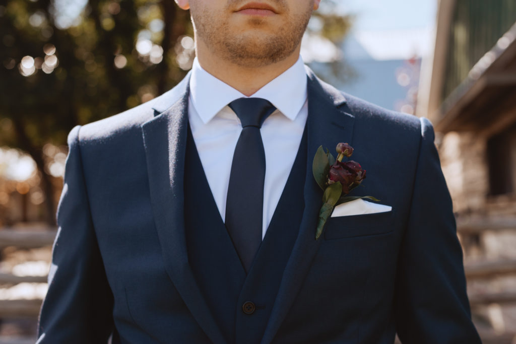 groom in navy 3-piece suit with burgundy boutonniere