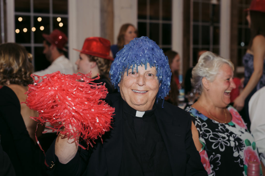 priest with pom poms at wedding dance party