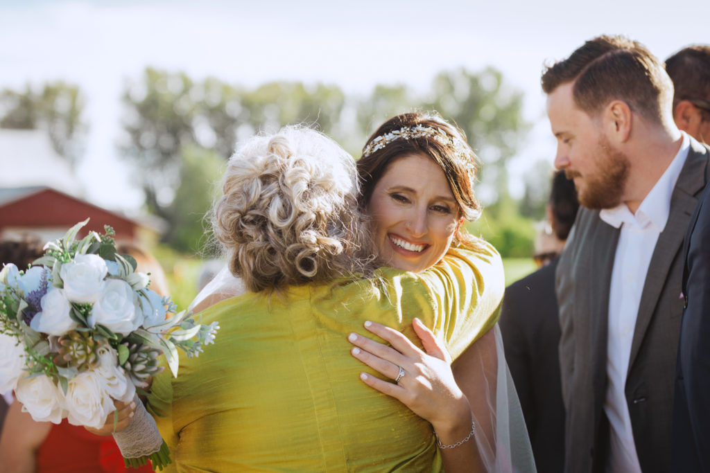 bride hugging the mother of the groom after outdoor wedding ceremony