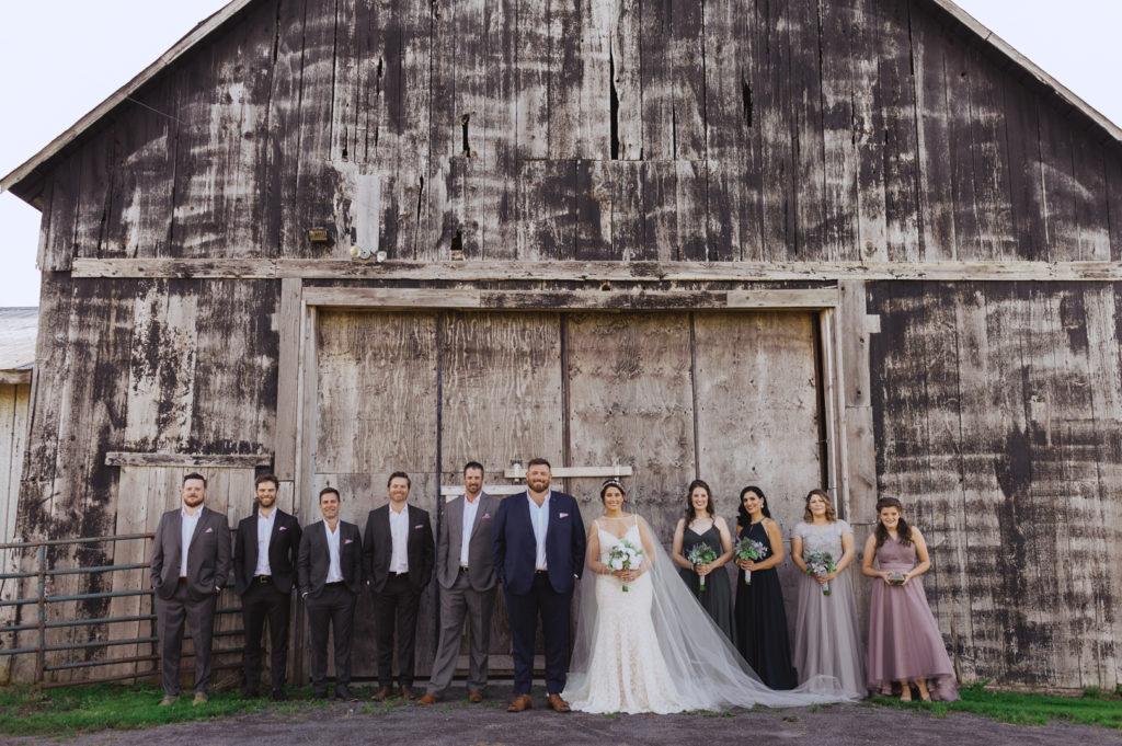 wedding party standing in front of old barn