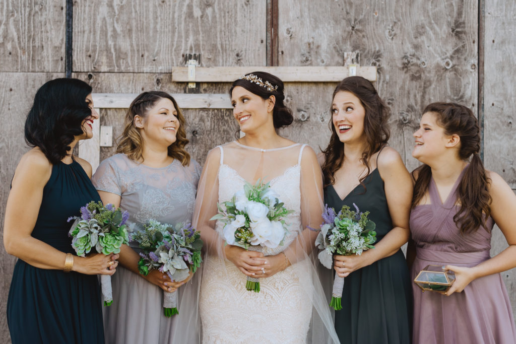 bridesmaids laughing with one another in front of barn door