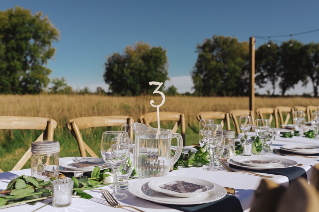 outdoor wedding reception with long harvest table in a field