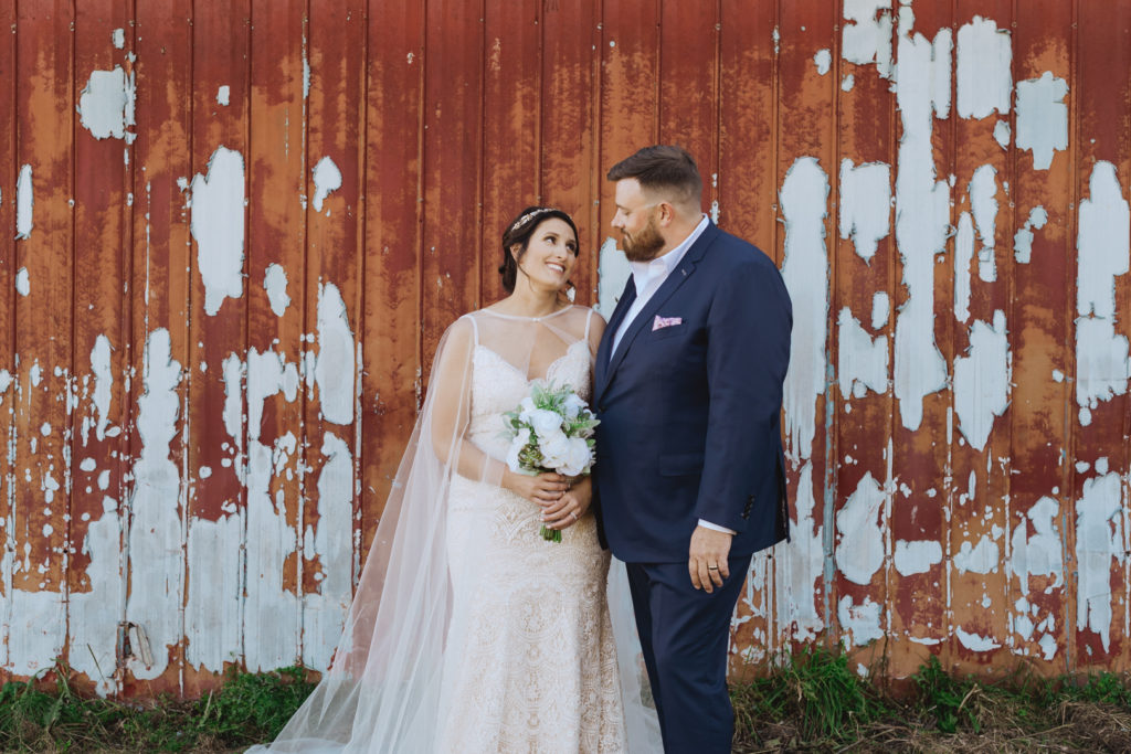 bride and groom in front of red barn