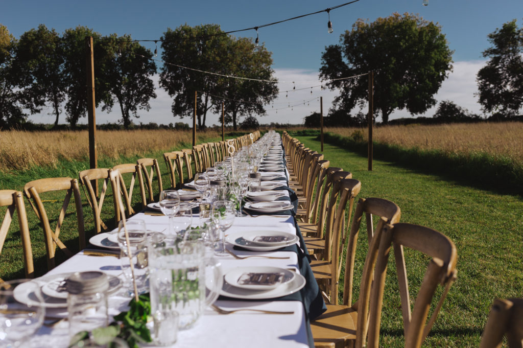 outdoor wedding reception with long harvest table in a field