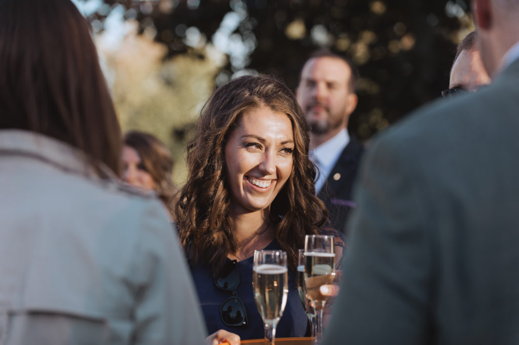 wedding guest passing around champagne to guests at backyard wedding