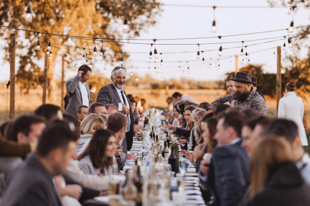 wedding guests sitting down to dinner at outdoor harvest table