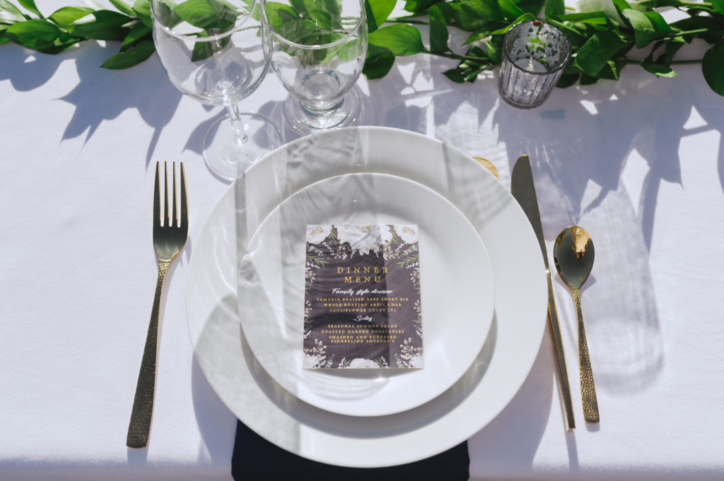 table setting with dinner menu and gold utensils