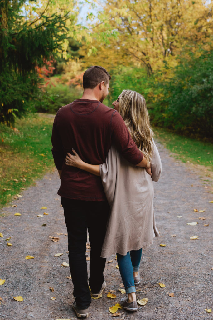 engaged couple walking with arms around each other down a gravel path