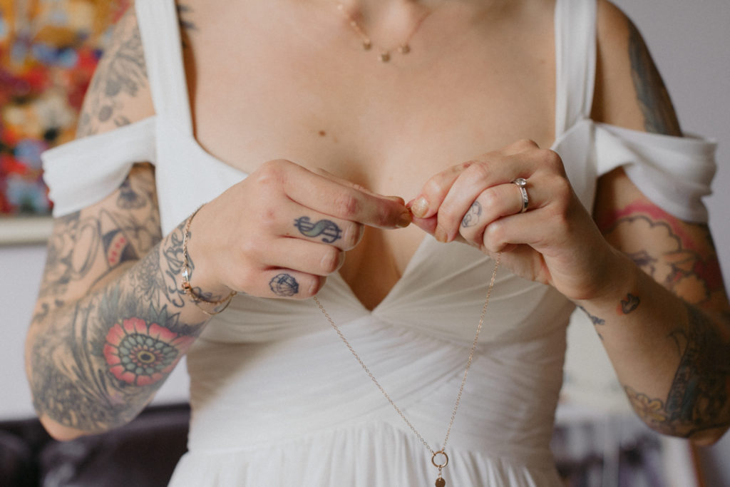 tattooed bride putting on her necklace