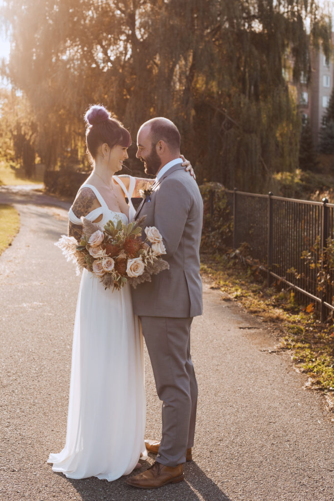 bride and groom cuddling on a path at sunset