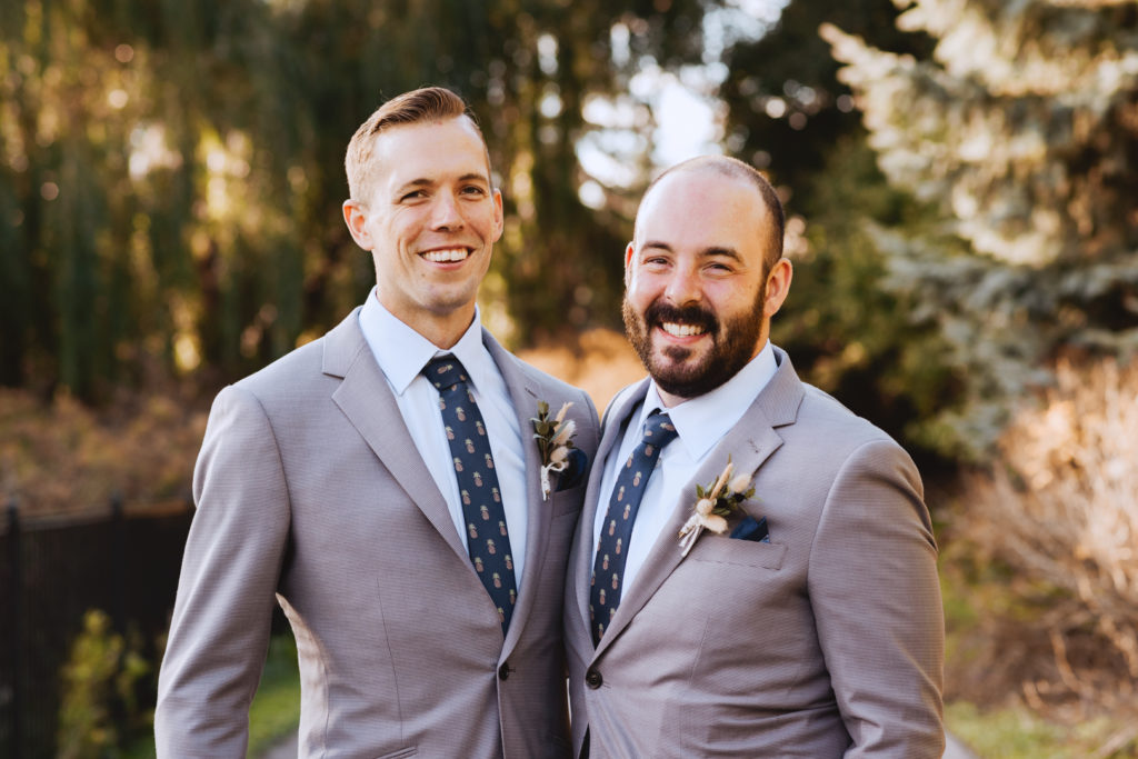 groom and best man smiling at sunset
