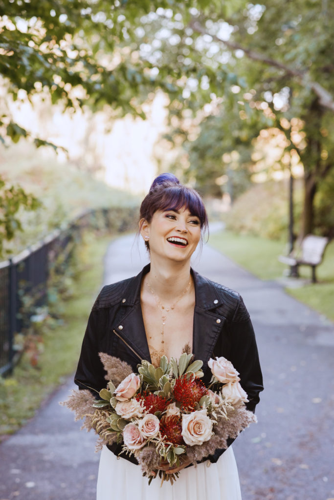bride wearing a leather jacket laughing in a park
