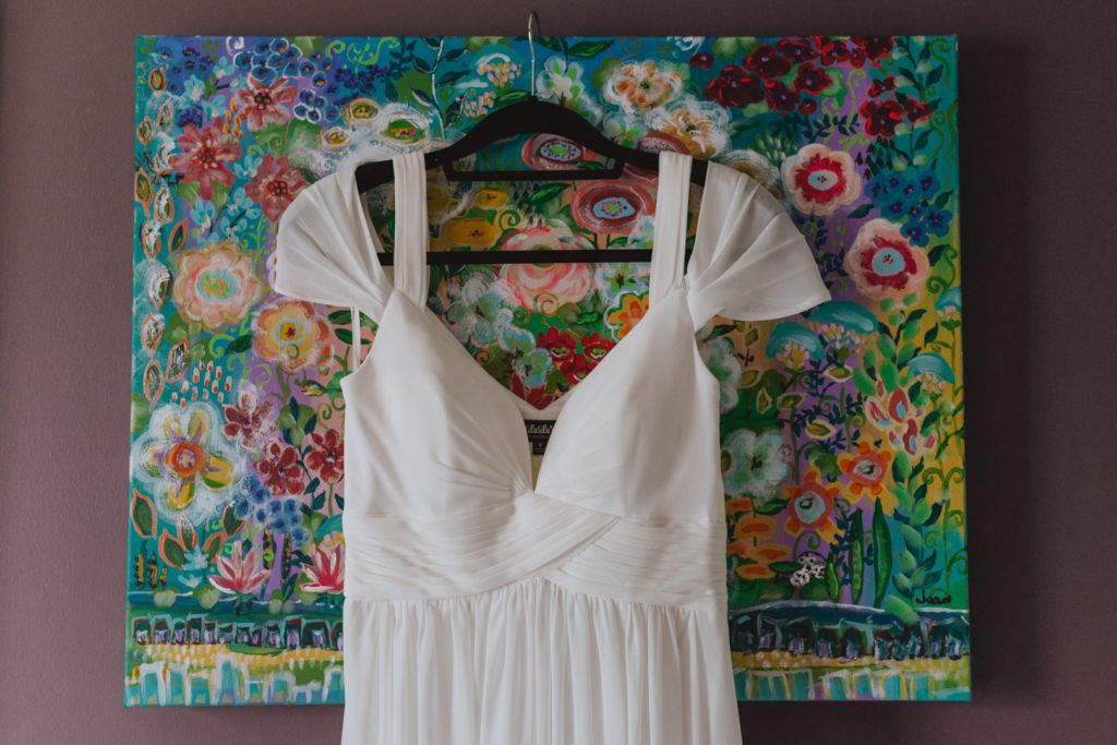 bride's vintage dress hanging on bright floral art