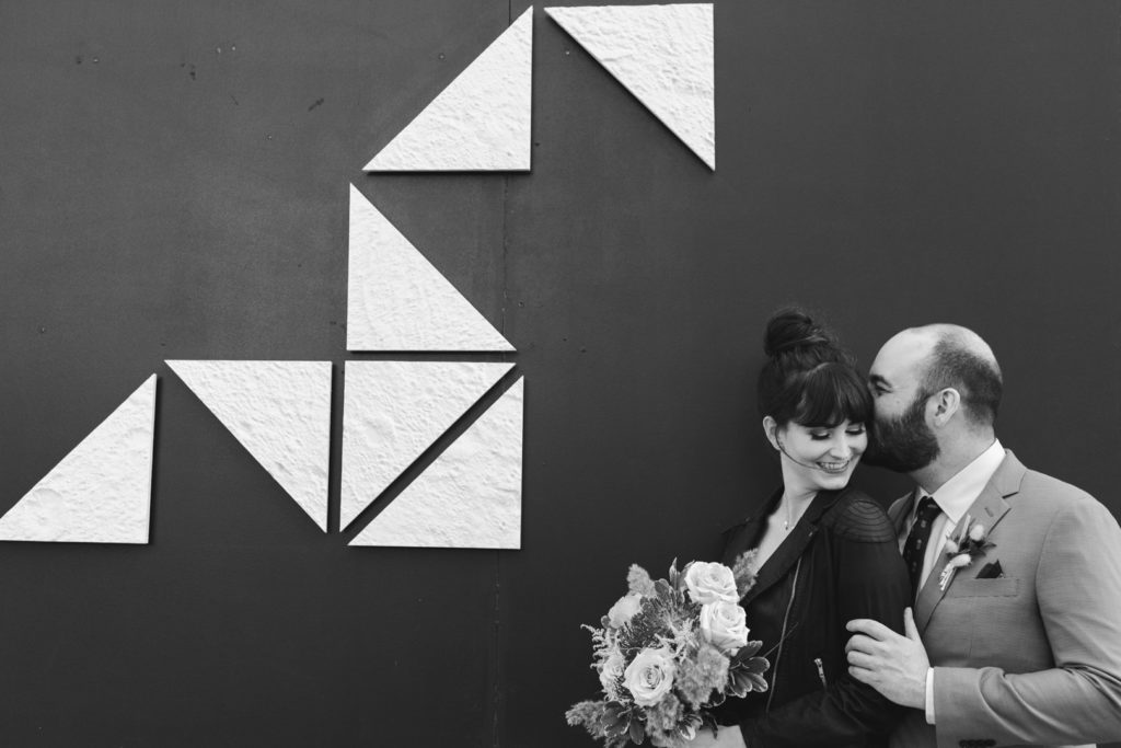 groom kissing bride in front of Cube Gallery