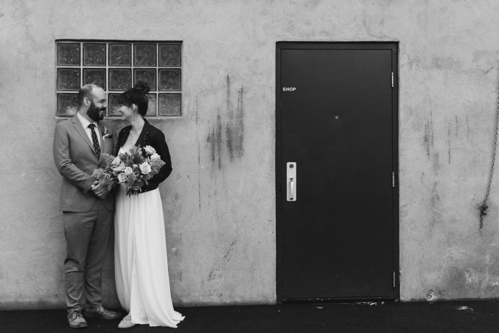 bride and groom smiling at each other by door and frosted glass window