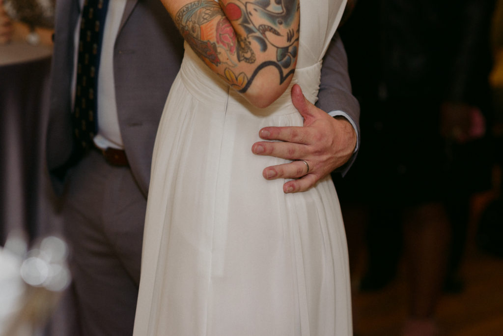 groom with his hand around his bride's waist