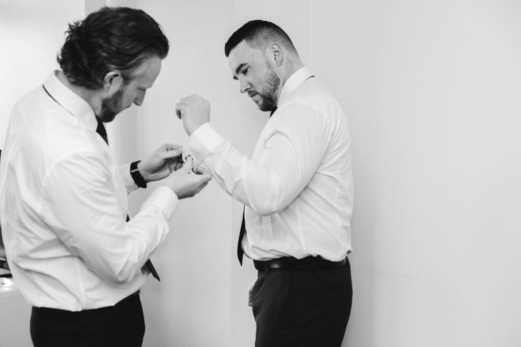 best man helping the groom put on cufflinks