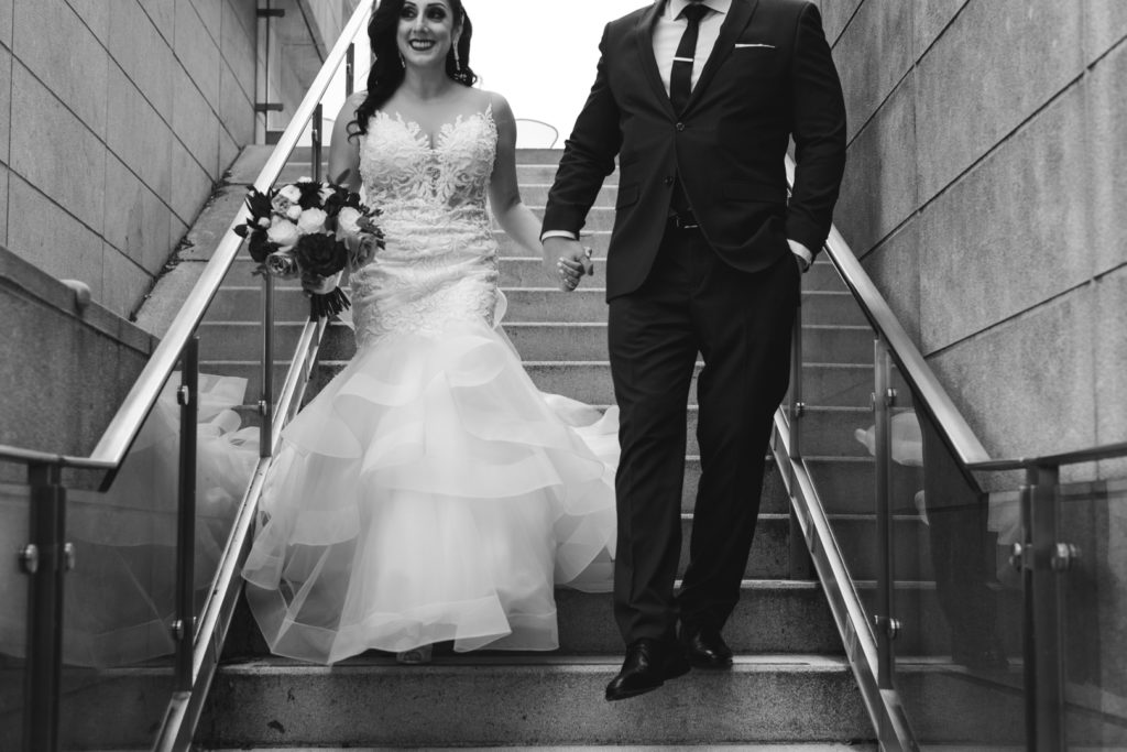 bride and groom holding hands walking down staircase