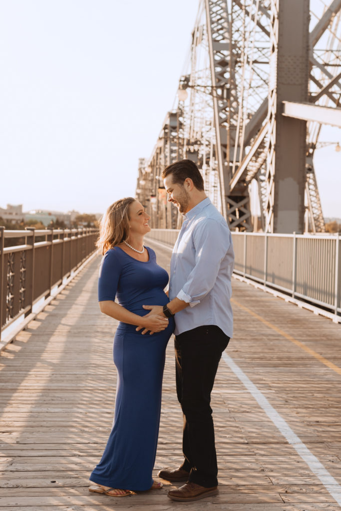 parents to be standing on wooden bridge at sunset