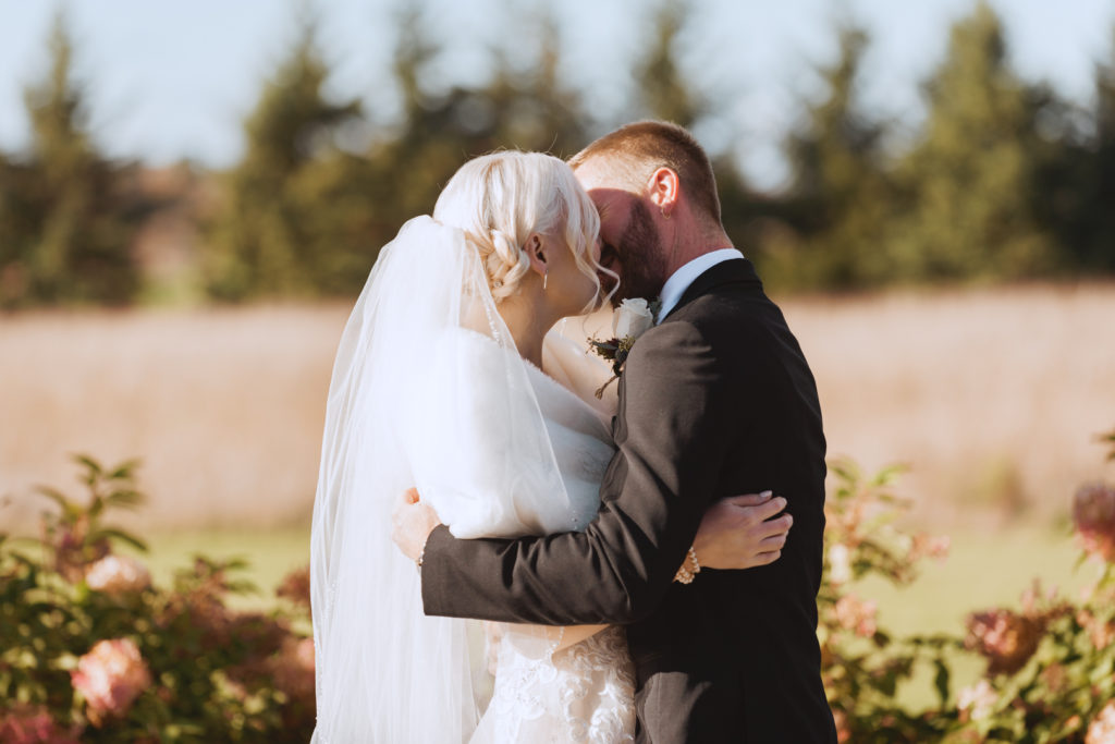 bride and groom first kiss at outdoor wedding ceremony