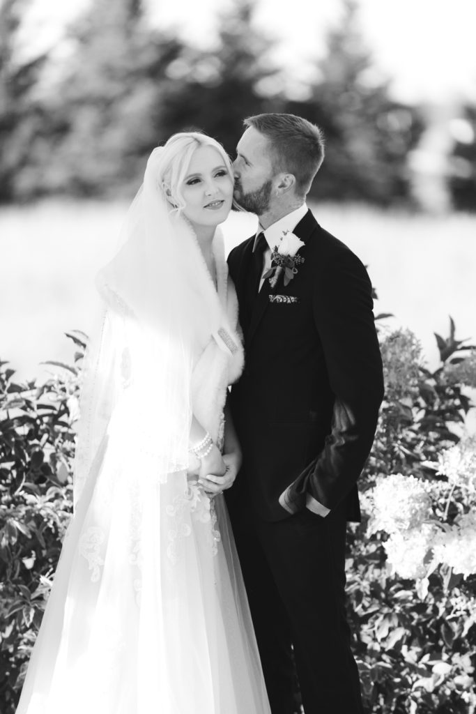 groom kissing the bride's cheek during outdoor wedding ceremony