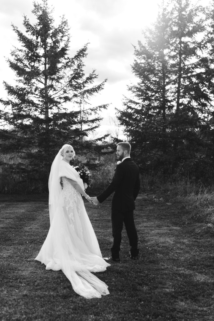 bride and groom holding hands walking in a field