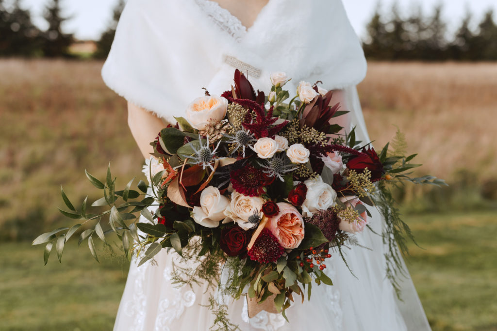 bride holding wild bouquet in a field at sunset