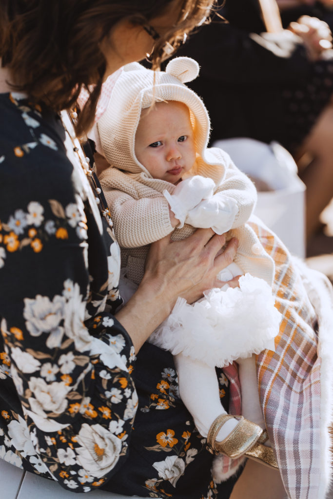 baby in white dress at outdoor wedding ceremony