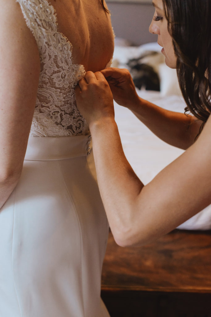 bridesmaid tying up the bride's wedding dress