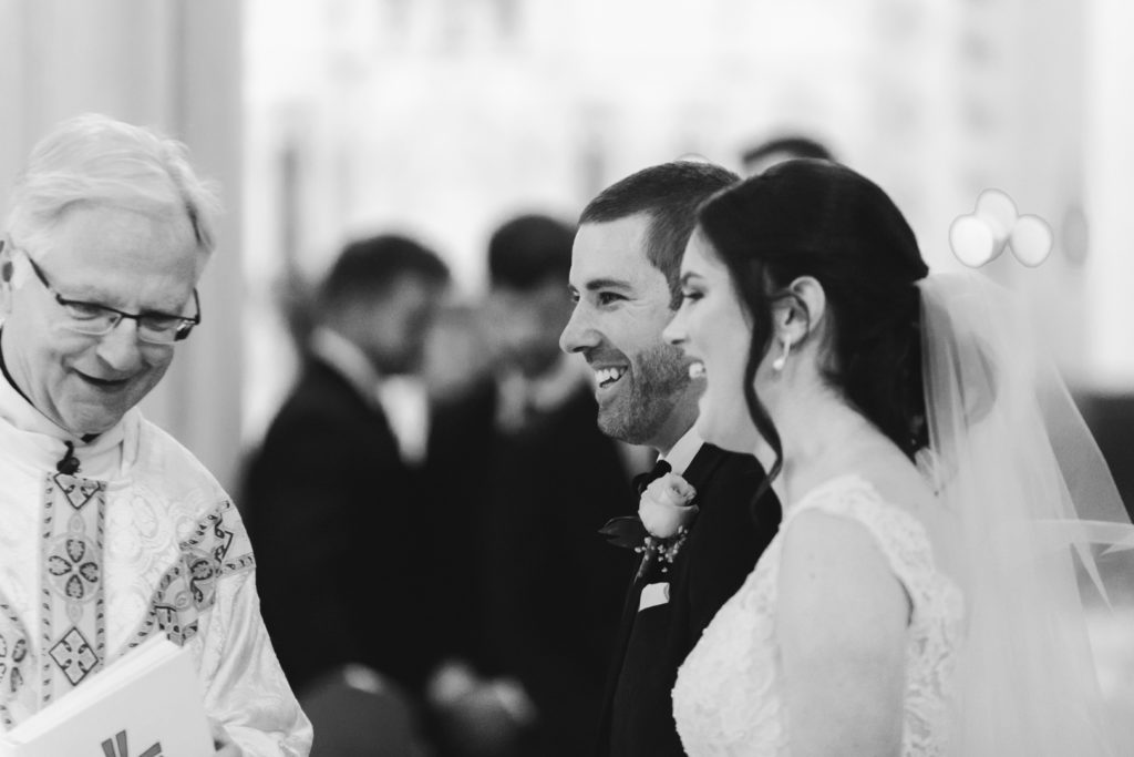 bride and groom laughing with priest