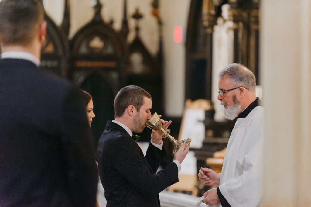 groom drinking the blood of christ during ceremony