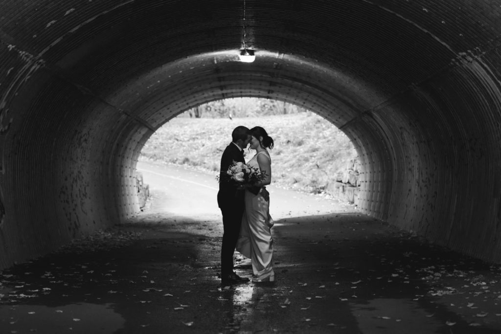 bride and groom in metal tunnel with light overhead