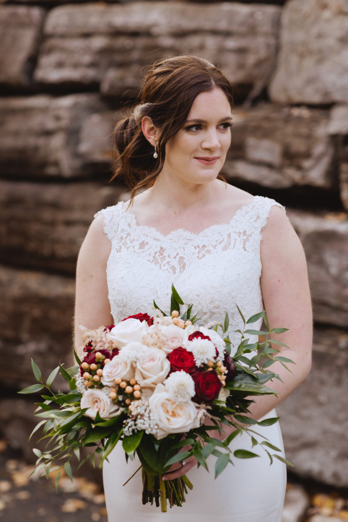 bride holding bouquet in front of large rock wall
