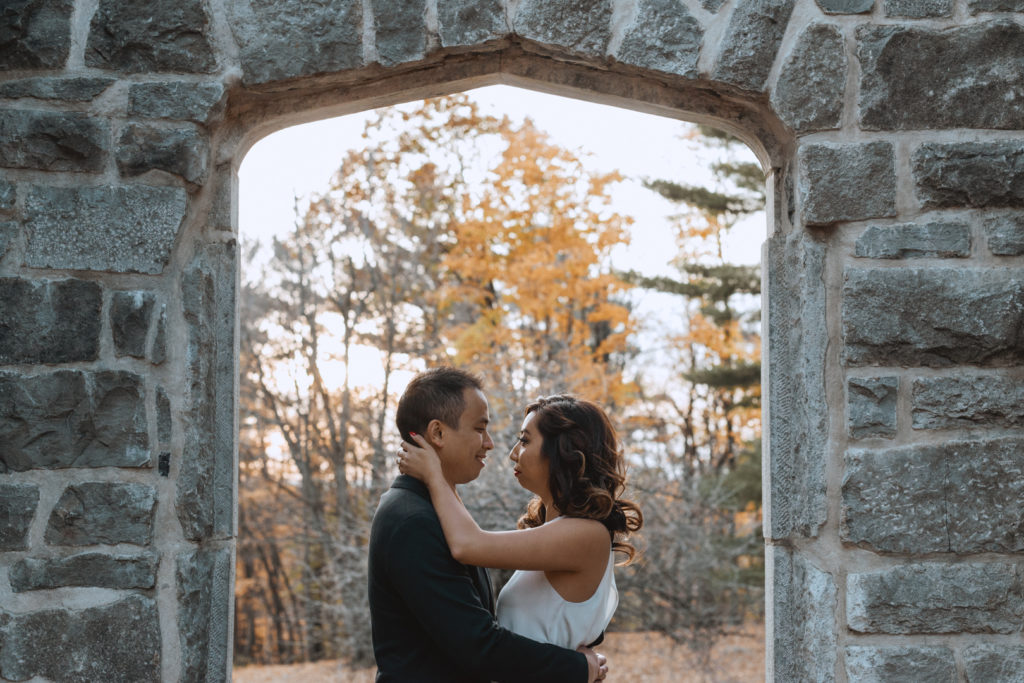 engaged couple standing under stone archway of ruins at Mackenzie King Estate
