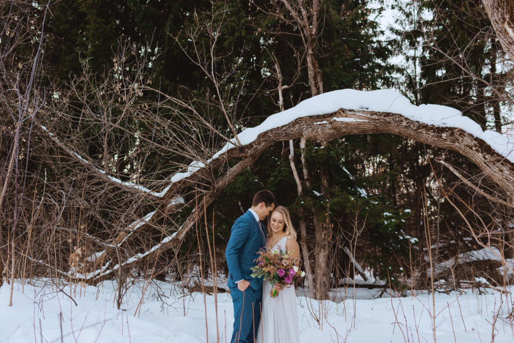 bride and groom standing in the forest in the winter