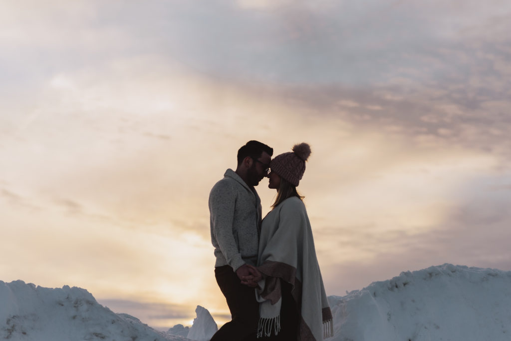 engaged couple at sunset on a snow covered hill