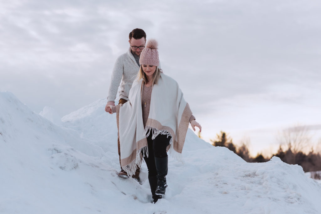 engaged couple walking down a mountain of snow