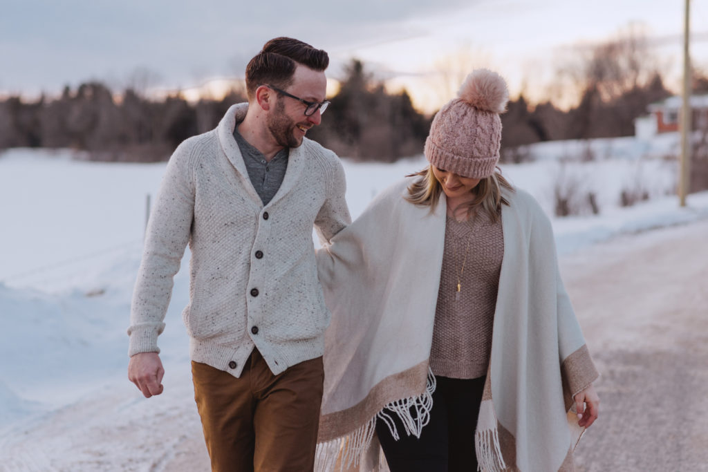 engaged couple walking down a dirt road in the winter at sunset