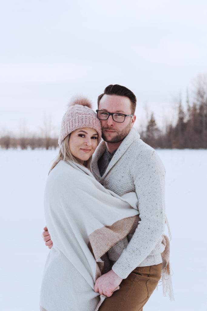 engaged couple in a snowy field at sunset