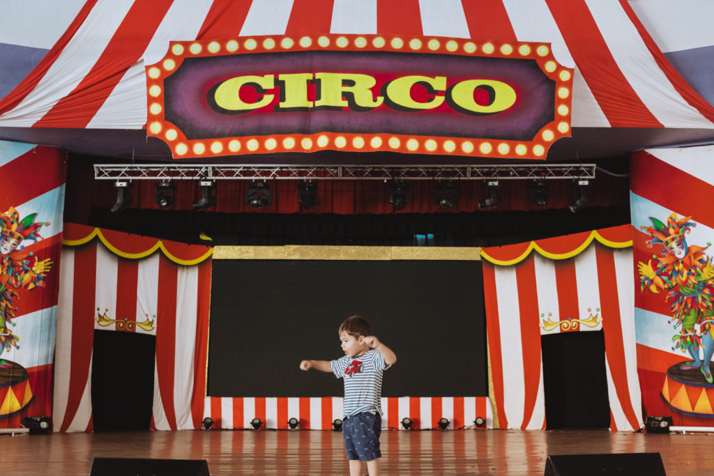 toddler playing on stage in front of circus sign
